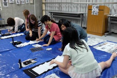 Meiji students teaching the finer skills of Japanese Calligraphy 