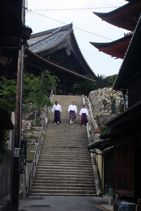 Men in kimonos descending a staircase.
