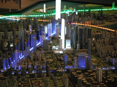 The miniature city is lit up in honor of it's modern architecture and smart planning. The green, orange and blue lights around them are roads leading to this metropolis.