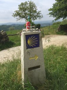 Camino directional and mile marker decorated with stones (prayers left behind), etc.